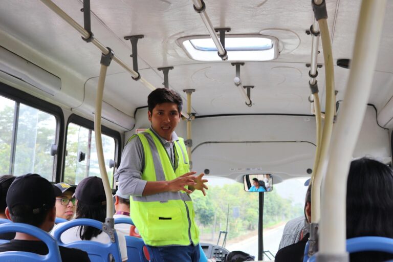 A tour guide on a bus in El Agustino, Lima, Perú, engaging with passengers.